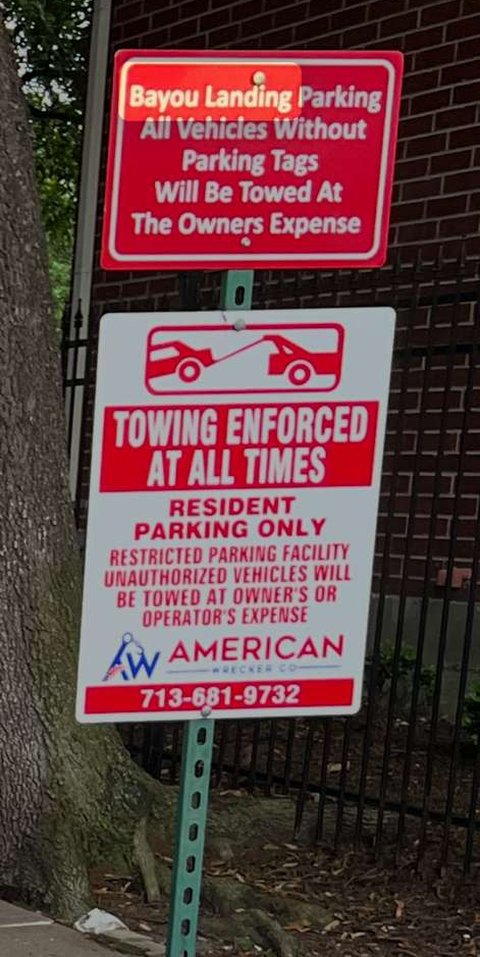 Posted towing signs at a Bayou Landing community entrance: a red Bayou Landing parking sign and a white American Wrecker Co. towing-enforced sign with the phone number 713-681-9732.
